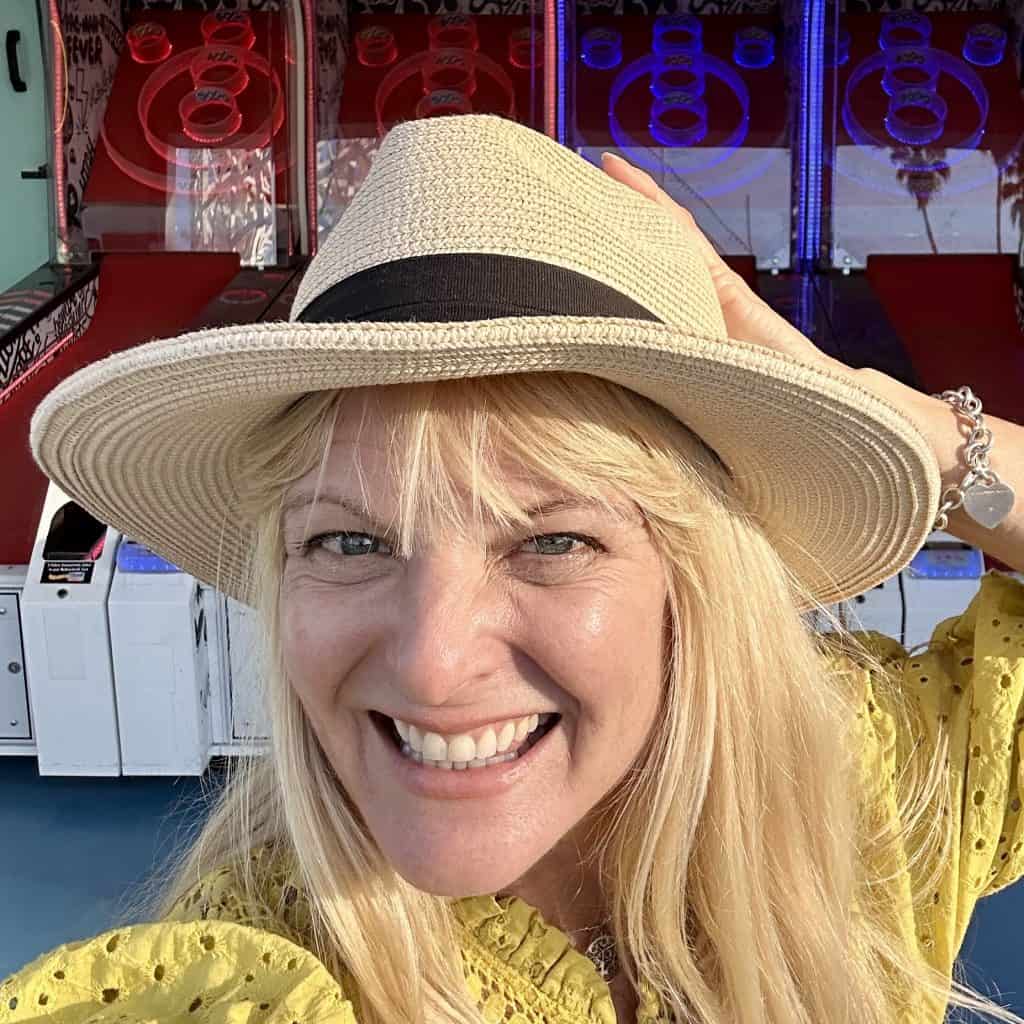 Kate Dana smiles in front of a row of Pac-Man skeeball machines, photo @katedana